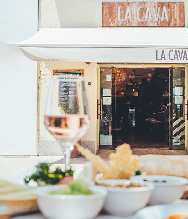 Mesa con tapas y vino con entrada de La Cava de fondo